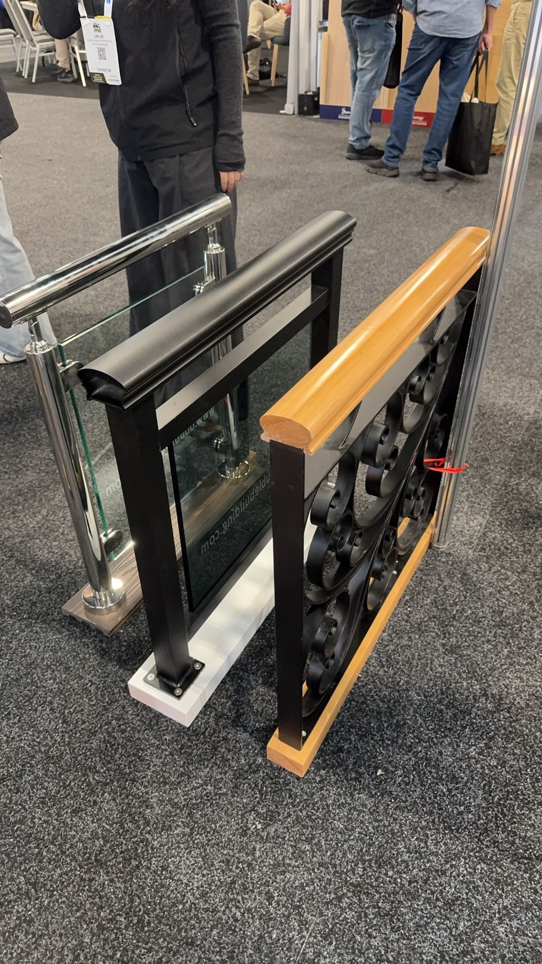 Railing samples at Sydney Build 2026: a frameless glass panel with a stainless top rail beside an ornate cast-iron baluster with a timber handrail