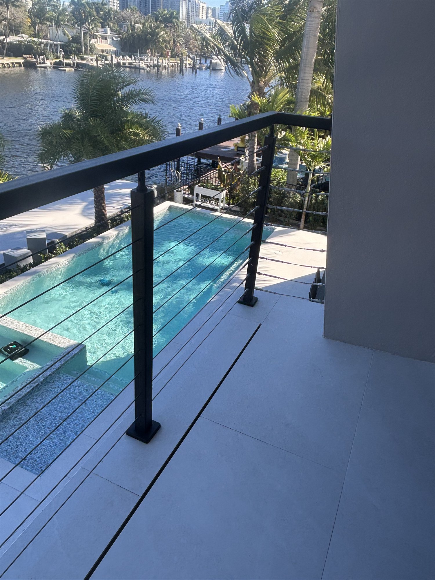 Black stainless steel cable railing on a Fort Lauderdale balcony overlooking a swimming pool and the canal beyond