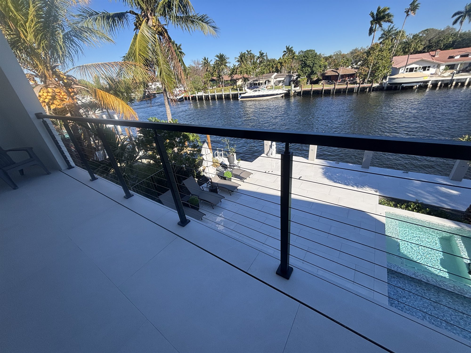 Black cable railing along a Fort Lauderdale balcony with boats moored on the canal in the background