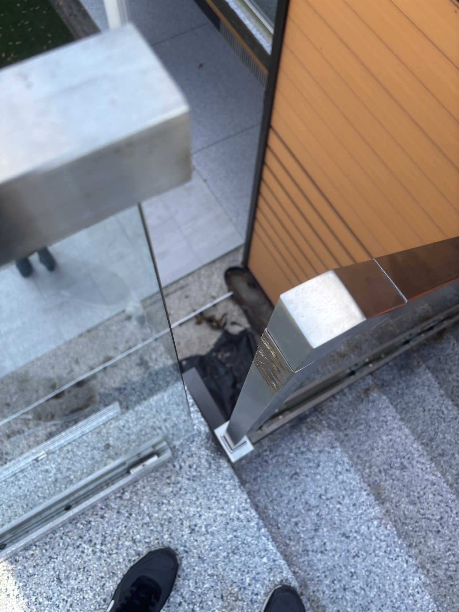 Close detail of a frameless glass panel set into a slim stainless base channel on stone steps at a Fort Lauderdale project