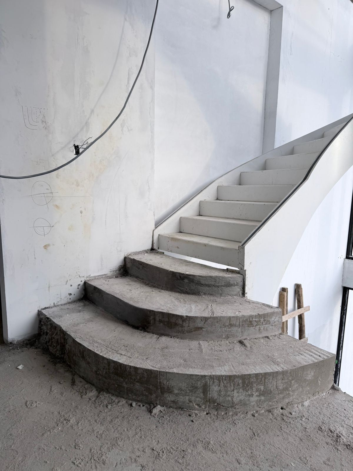 Curved staircase under construction in Suriname with fan-shaped concrete winder treads forming at the base of the flight