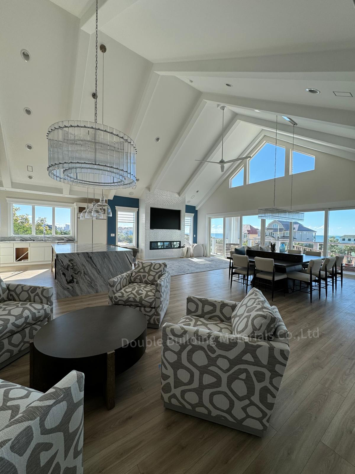 Vaulted great room with a high cathedral ceiling, twin drum chandeliers, oak floors and a wall of windows opening to the water in Virginia