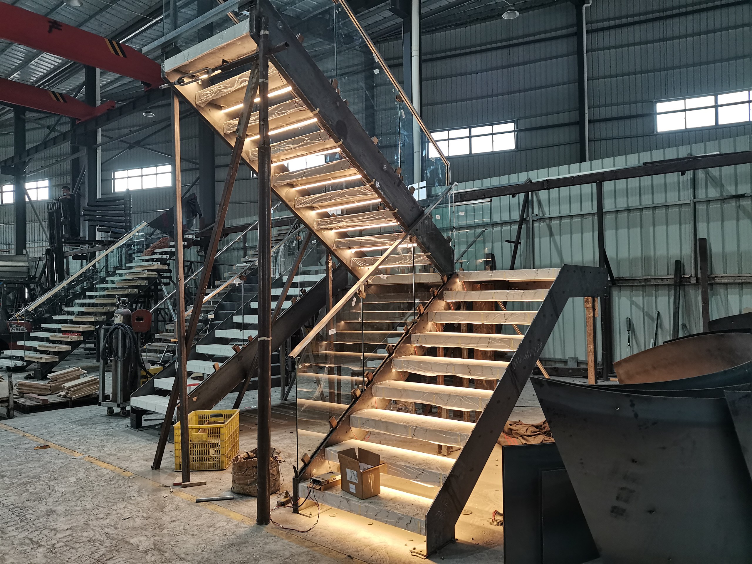 Full multi-flight stone staircase stood up for trial assembly in the DBM Guangdong workshop, with under-tread LED step lighting lit
