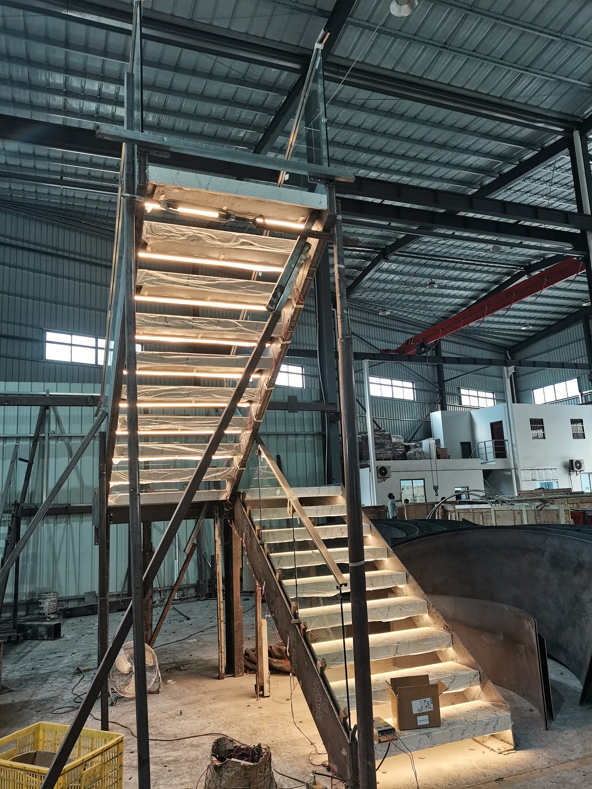 Trial-assembled stone staircase in the DBM Guangdong workshop with warm LED light glowing under each stone tread