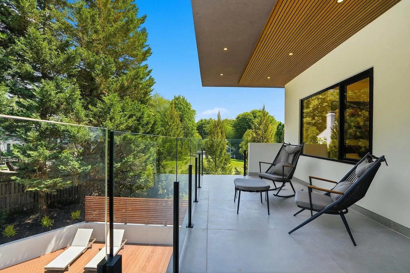 Glass balcony railing with slim black posts and no top rail along a covered upper balcony of a modern home in Virginia