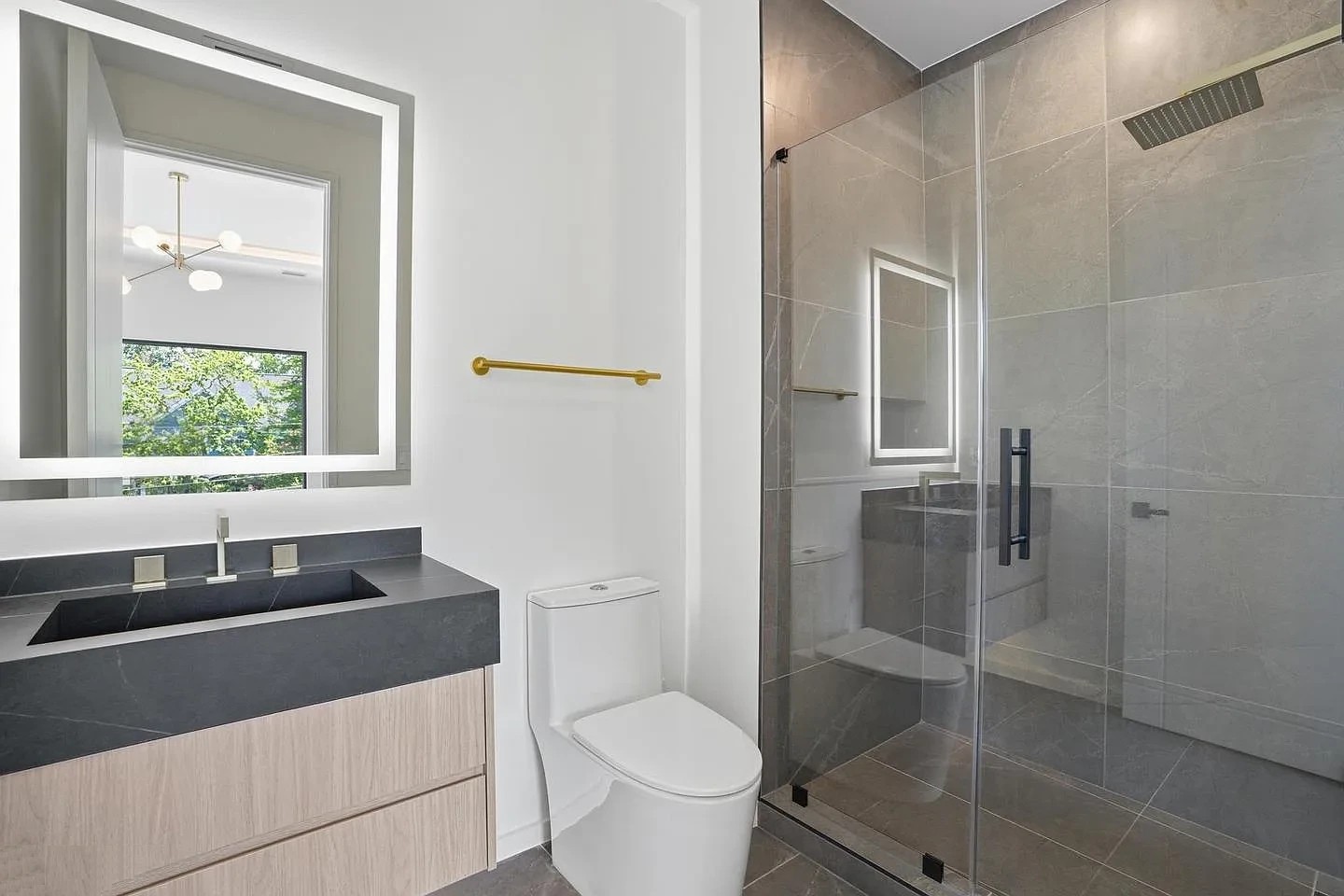 Frameless glass shower enclosure with a hinged door, black hinges and a long black pull in a modern Virginia bathroom