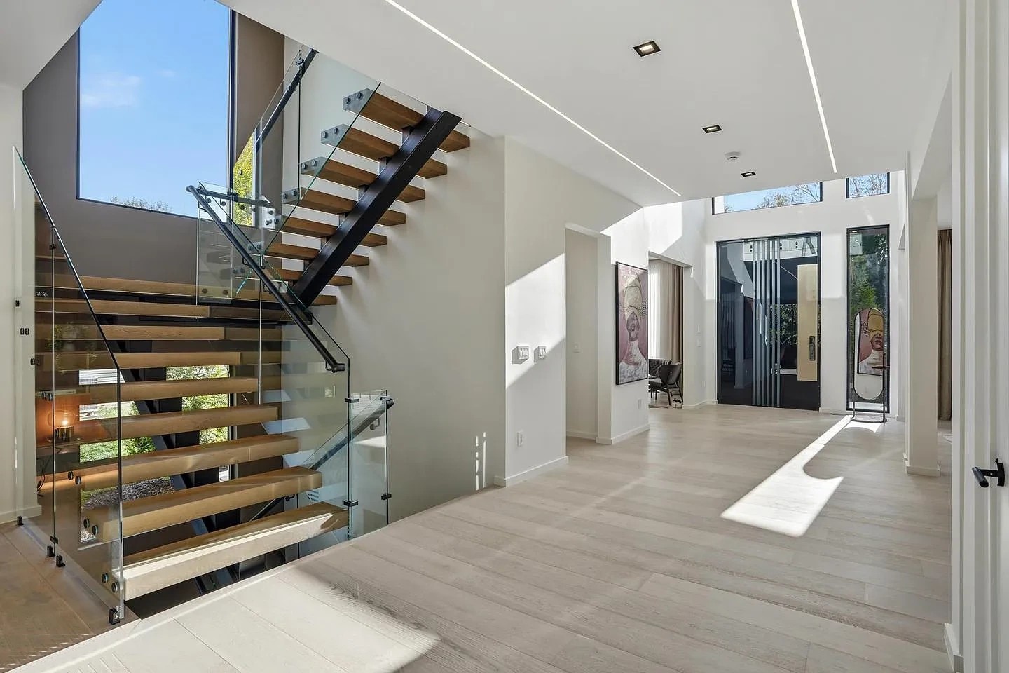 Square-tube stair with wood treads and side-fixed glass held by bolted plates at each tread, next to the foyer of a modern Virginia home