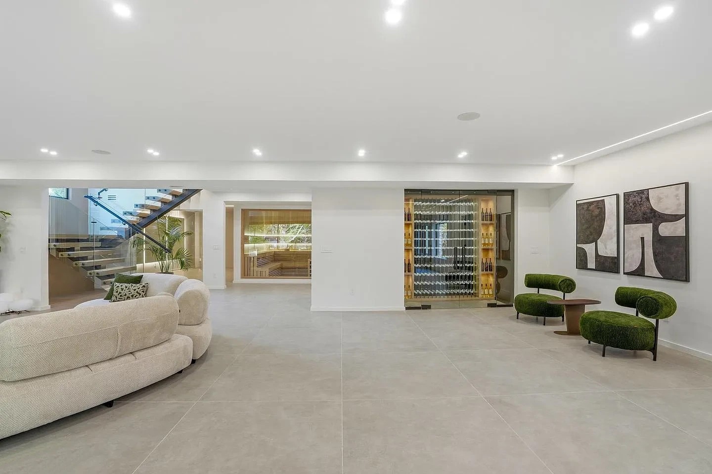 Lower-level lounge of a modern Virginia home with a glass-fronted wine room, a sauna with a glass front and the square-tube stair
