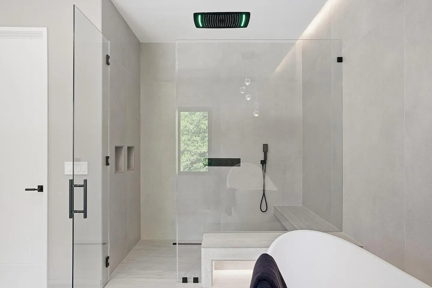 Walk-in frameless glass shower with a glass door and fixed panels in the main bathroom of a modern Virginia home