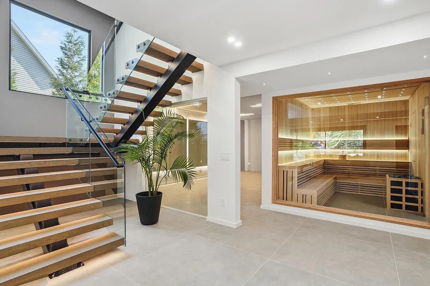 Square-tube staircase with glass railing and LED light under the treads, beside a glass partition and a glass-fronted sauna in a Virginia home