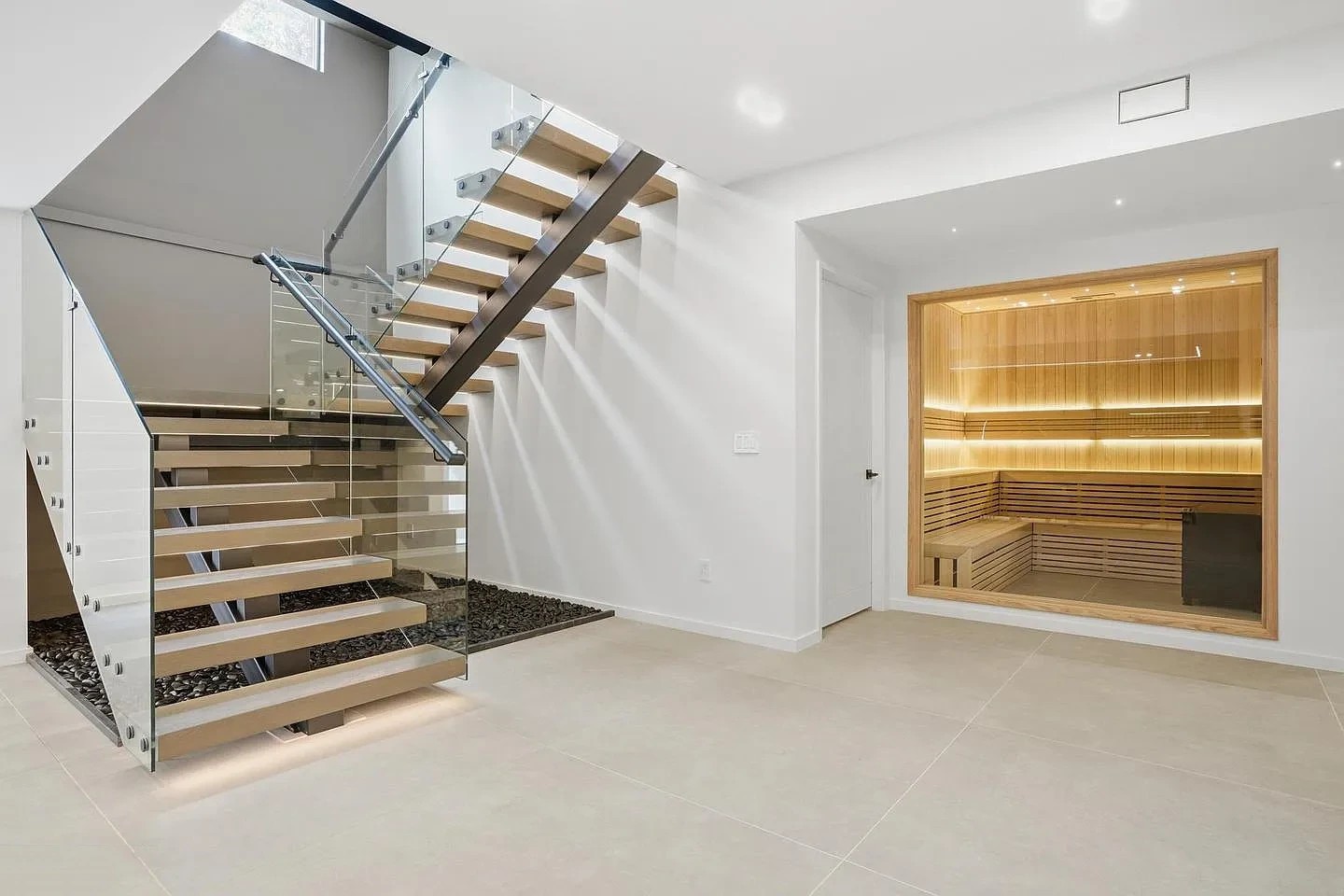 Modern staircase with glass railing on a dark square-tube spine with wood treads, beside a glass-fronted sauna in a Virginia home
