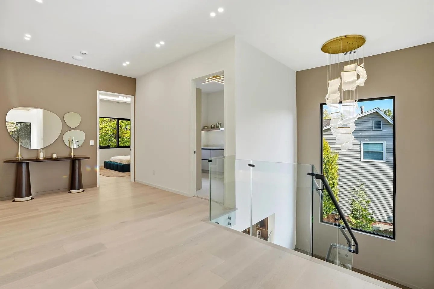 Upper landing of a modern Virginia home where a frameless glass guard with a black handrail meets the stair opening