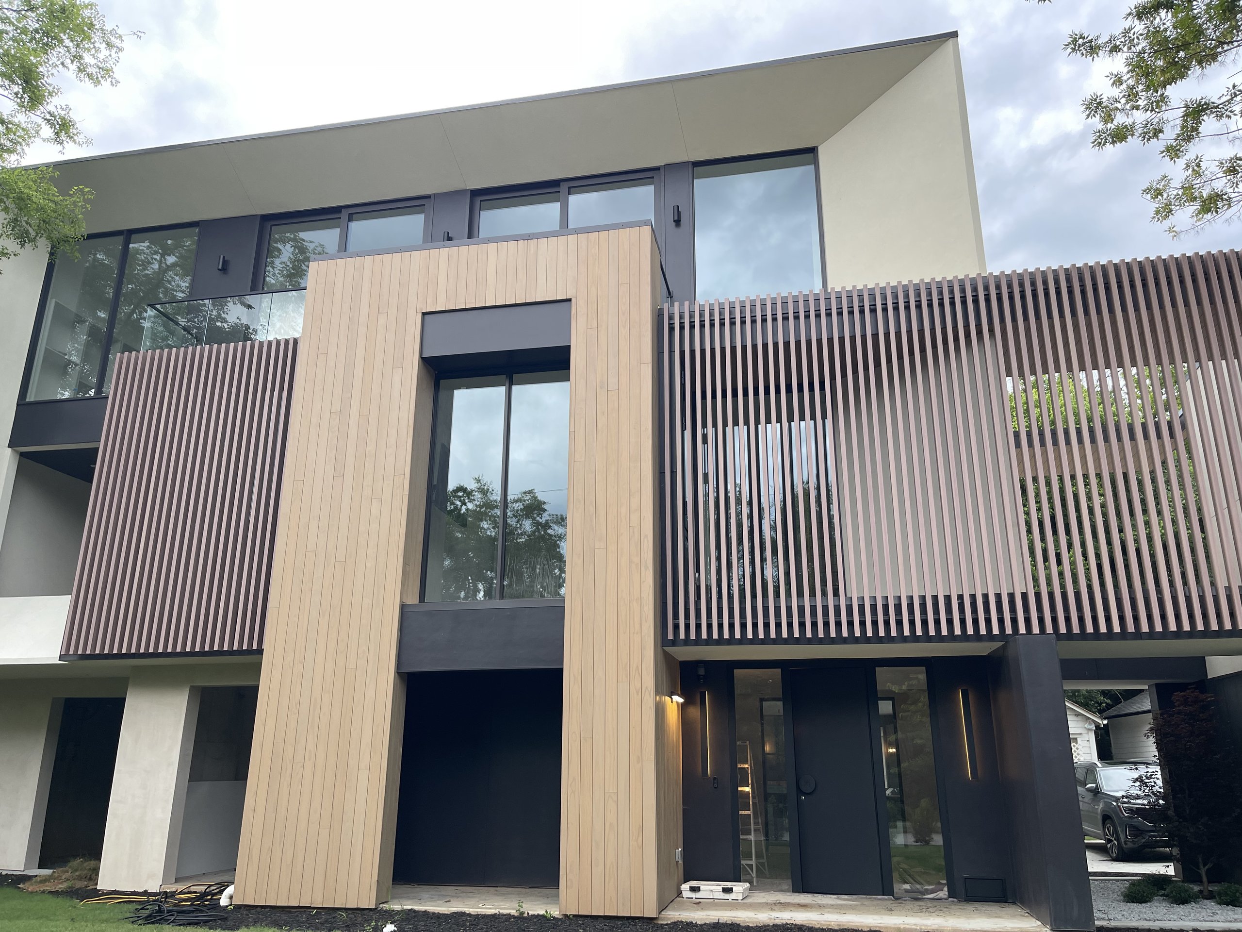 Modern Atlanta home seen from the front garden, with a frameless glass balcony railing on the upper floor at the left