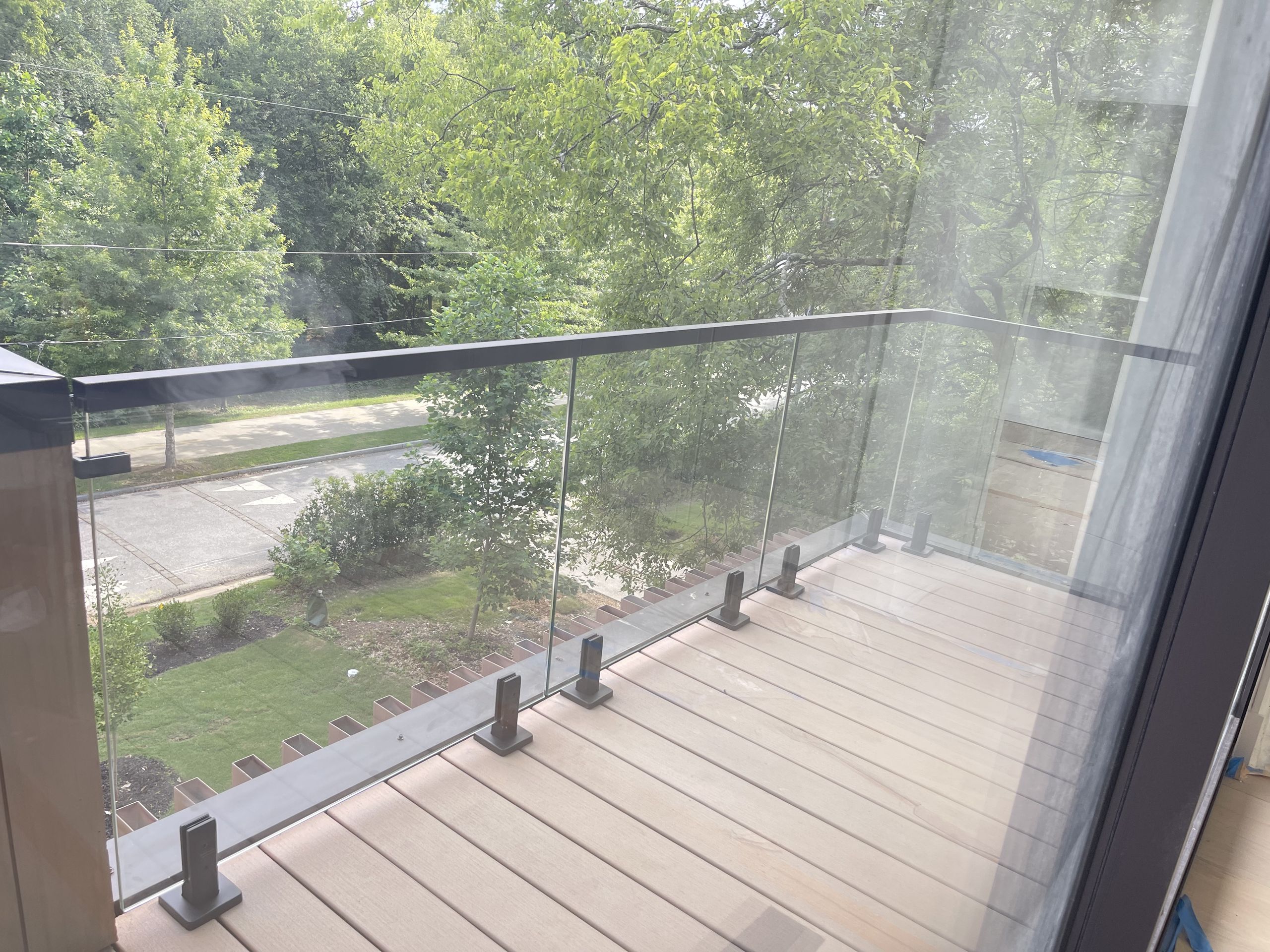 Spigot glass railing on an Atlanta balcony, with dark square spigots on the deck boards, a black top rail and a corner return