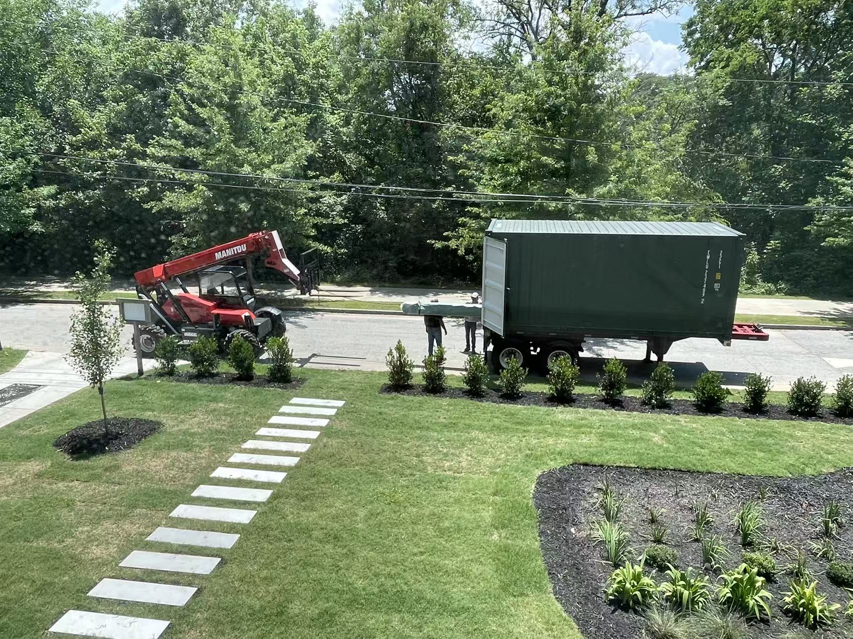 Shipping container with the Atlanta staircase and railing order parked at the street, a telehandler on hand to unload