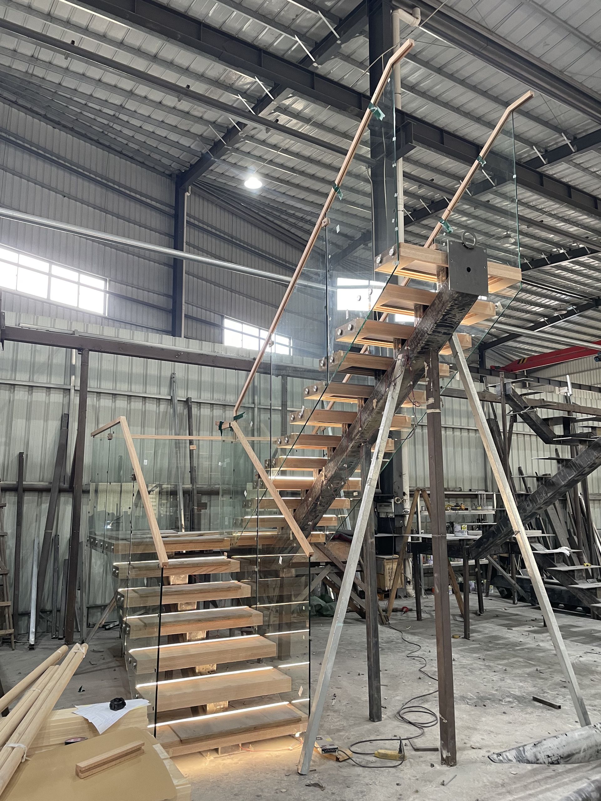 Trial assembly of the Hawaii U-shaped staircase in the DBM Guangdong workshop, with red oak treads, glass, wood handrail and step lights on