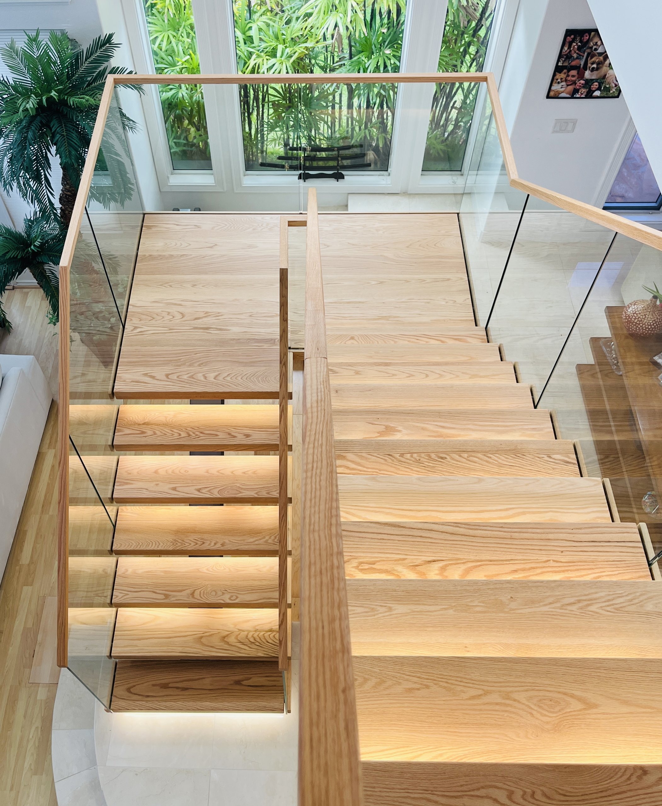U-shaped red oak staircase seen from above, two flights side by side turning on a red oak landing, with step lights glowing under the treads